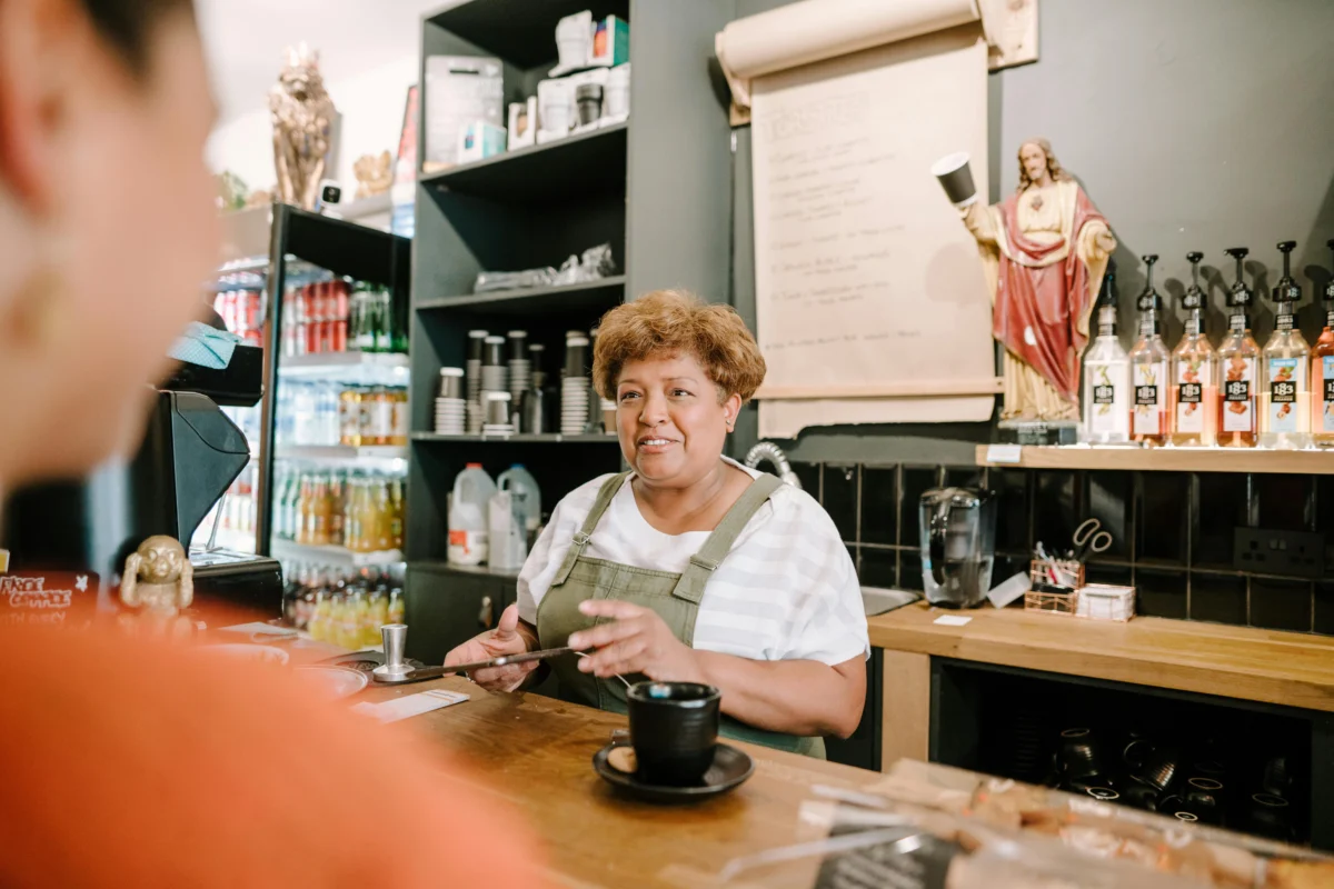 A woman helping a customer from the register at a coffee shop.