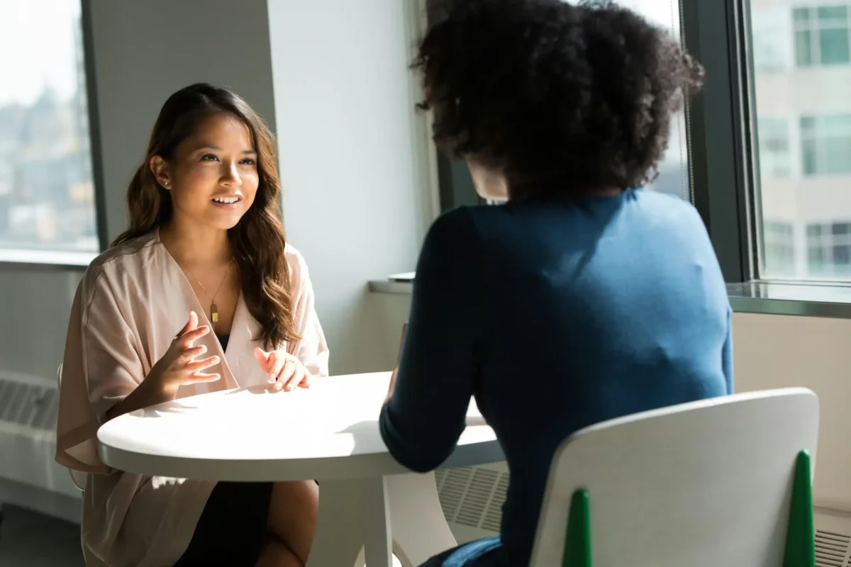 Deux femmes à une table, en conversation.