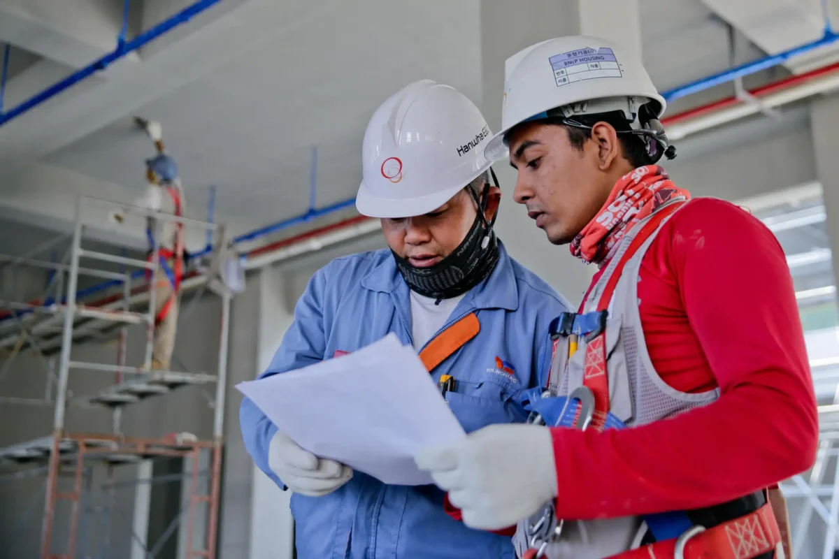 Deux travailleurs de la construction lisant un plan.