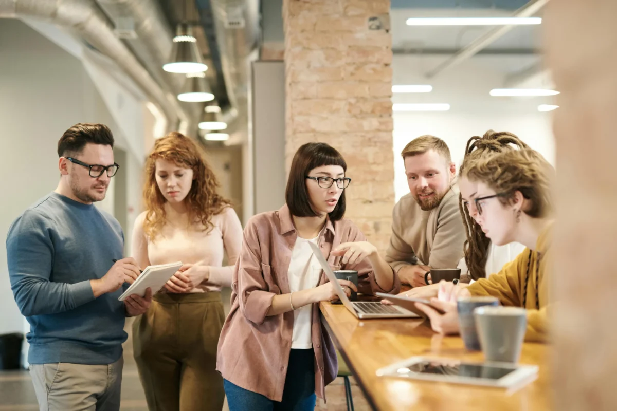 Several employees engaging in different work conversations in a communal office area.