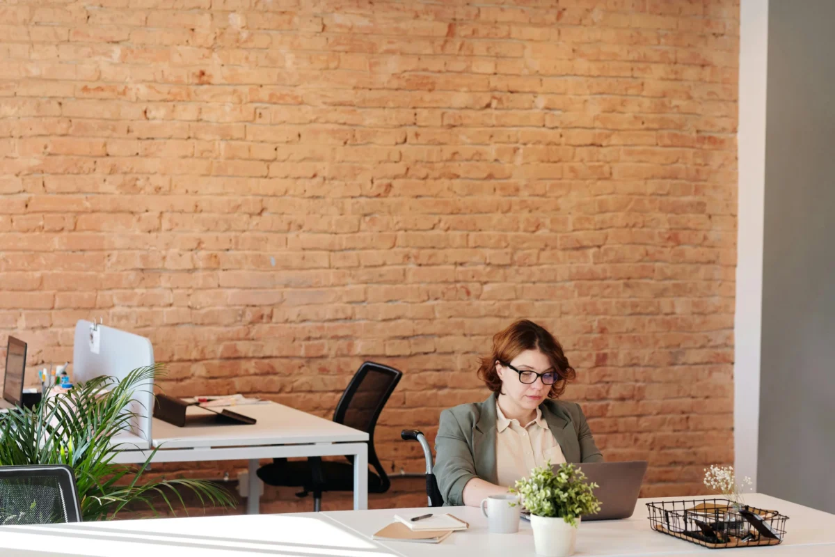 A woman in a wheelchair working on her laptop in an open concept office.