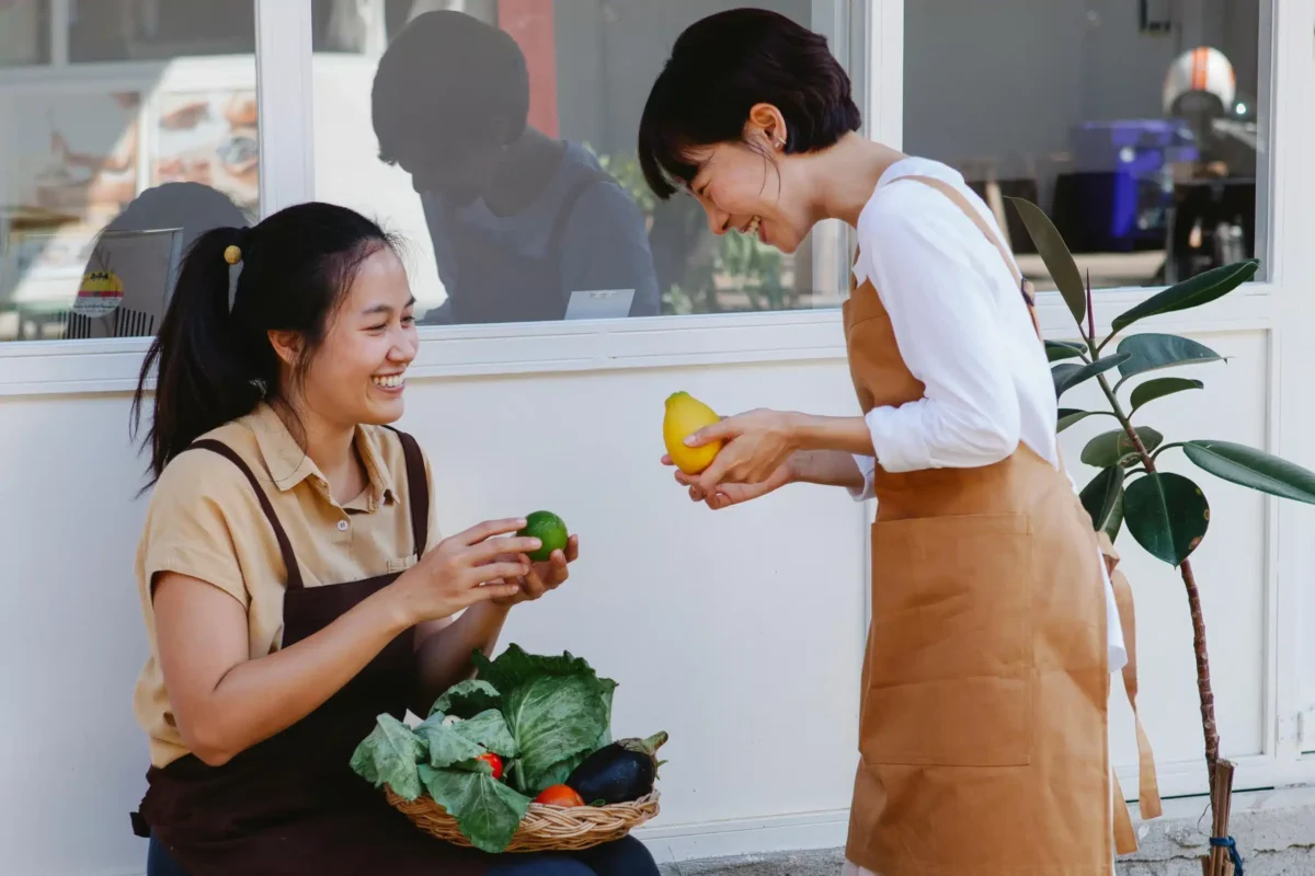 Two women talking while holding produce.