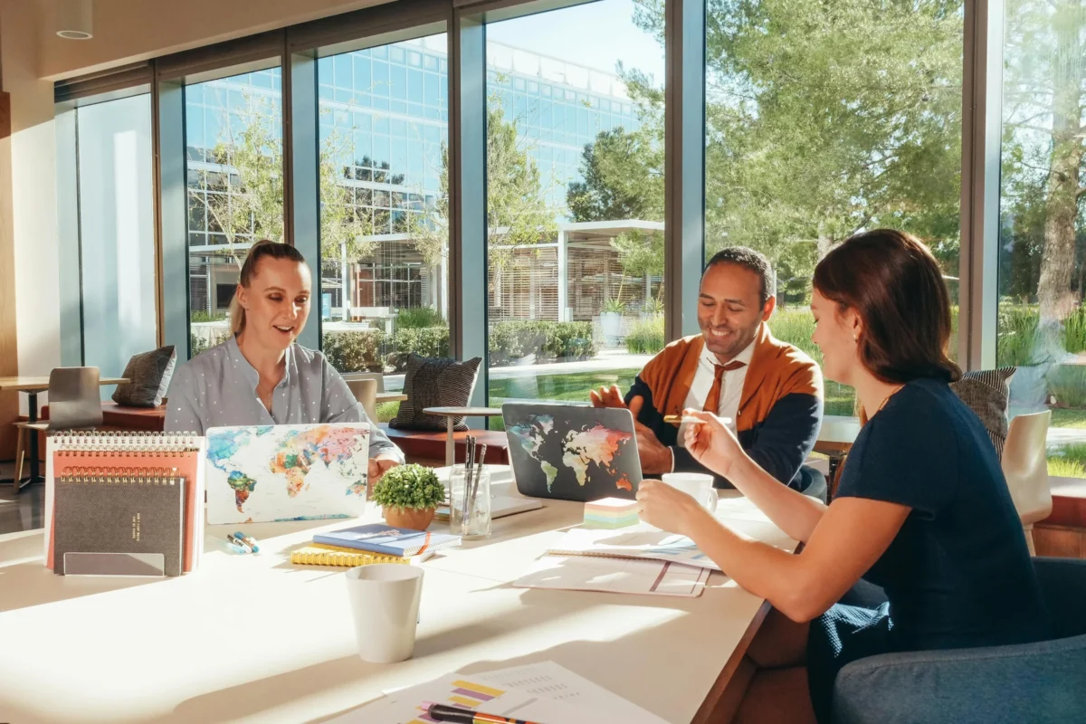 Team of three people meeting in a shared space in an office.