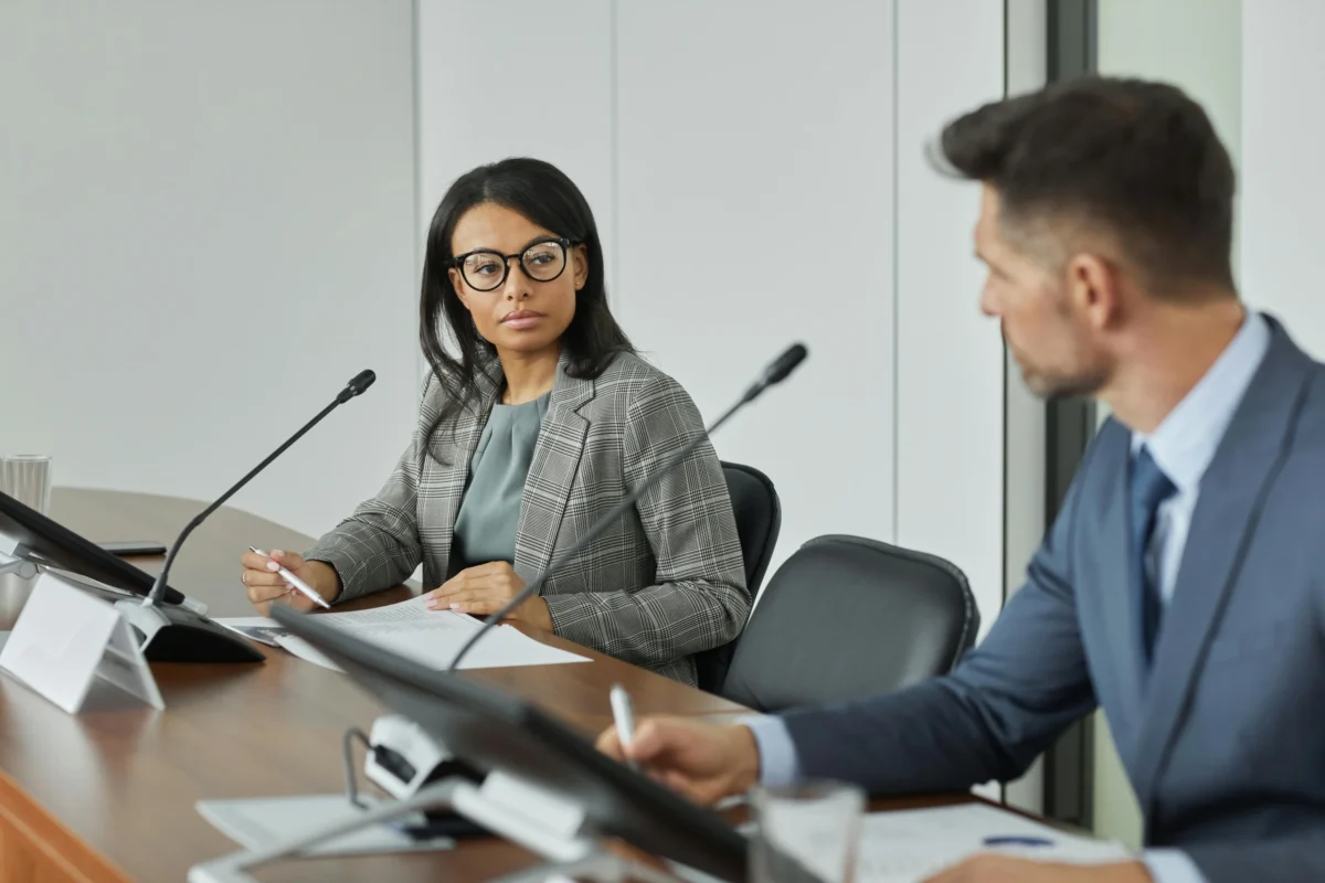 A female and male executive engage in a serious discussion at a meeting.