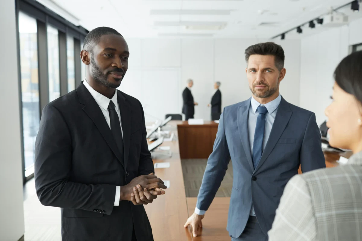 Several executives engaging in different conversations in a meeting room.