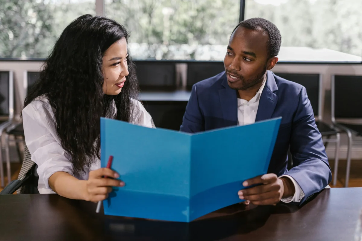 A female and male colleague look over a report together.
