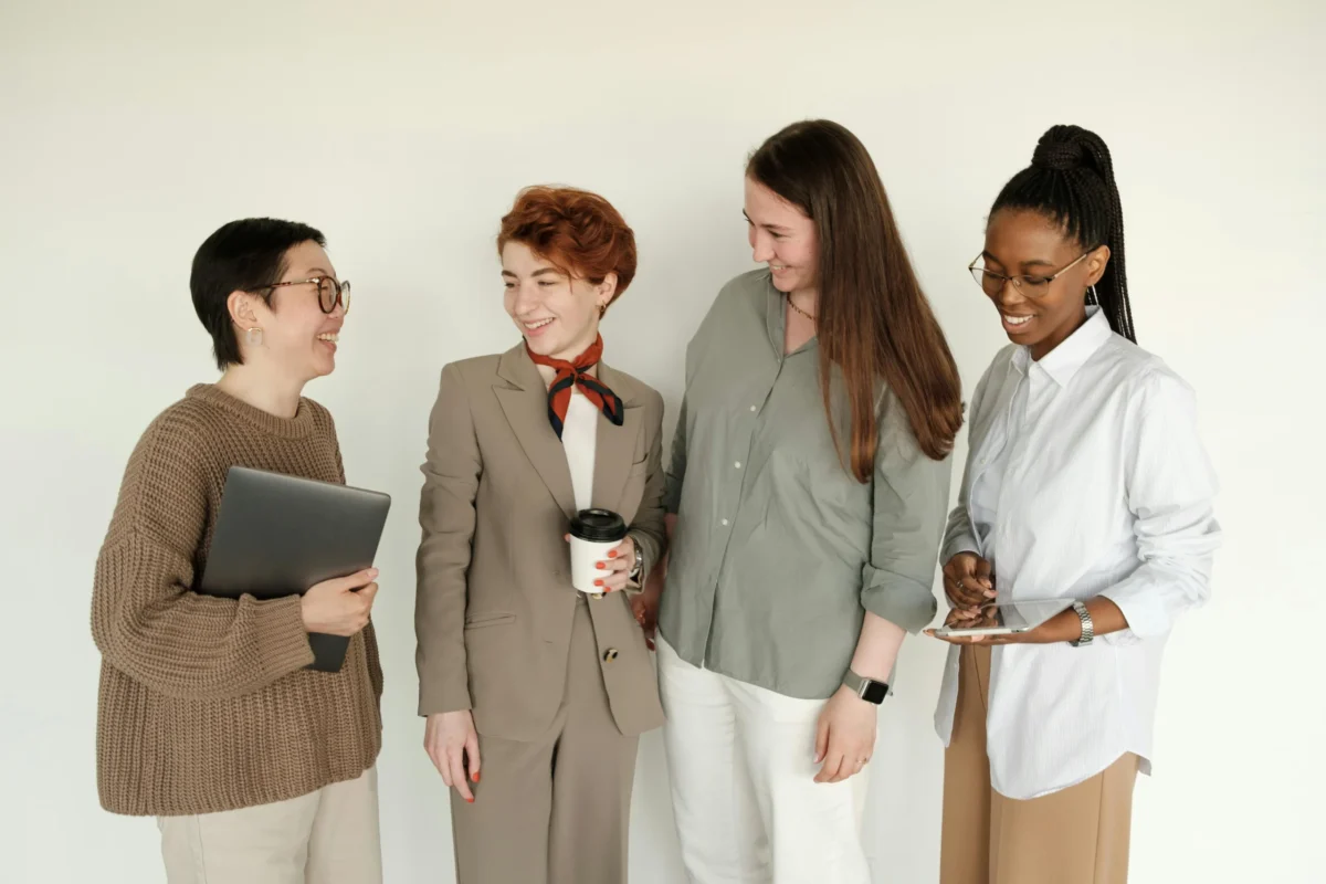 A group of diverse women engaging in a conversation at an office.