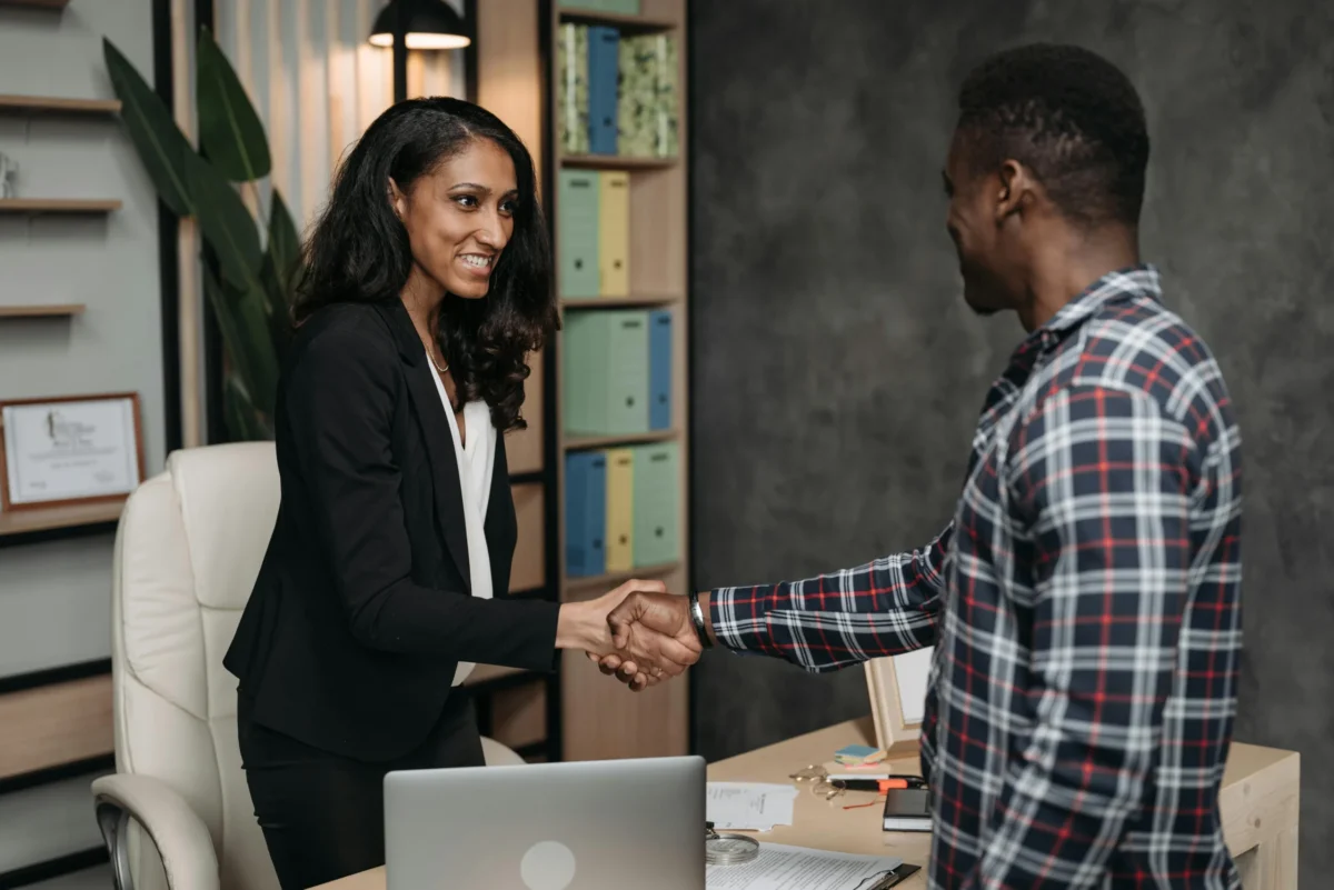 A female lawyer shakes her male client’s hand in her office.
