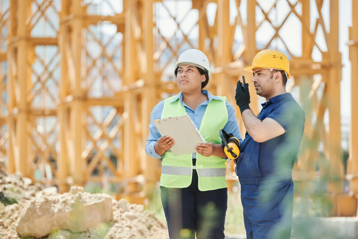A woman and man radioing on a construction site.