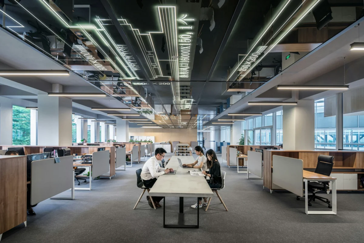 Trois employés travaillent à la même table d’un bureau ouvert.