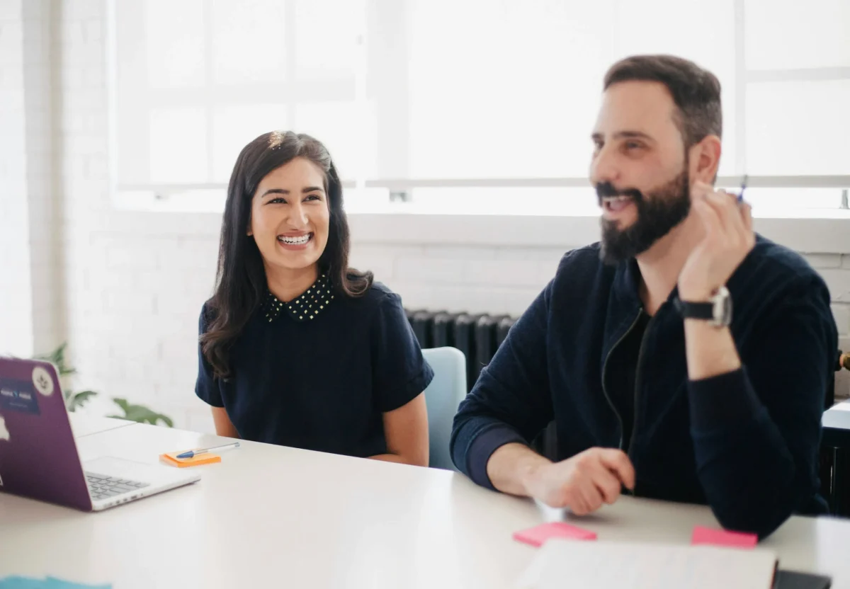 Une femme et un homme au travail qui sourient.