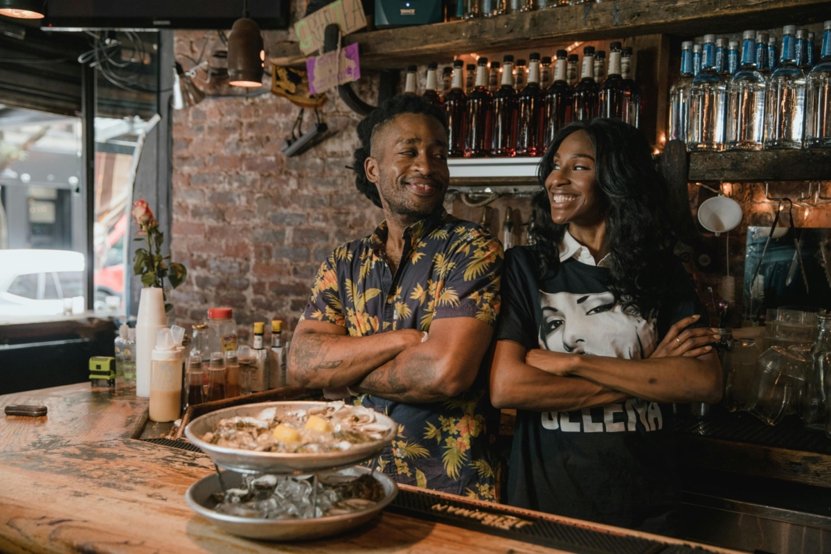 Man and woman smiling at each other at a bar counter.