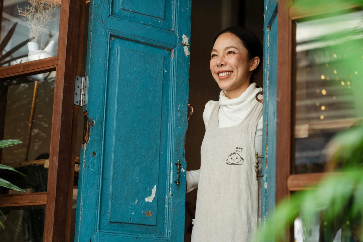 Female shop owner happily opening the door to her business.