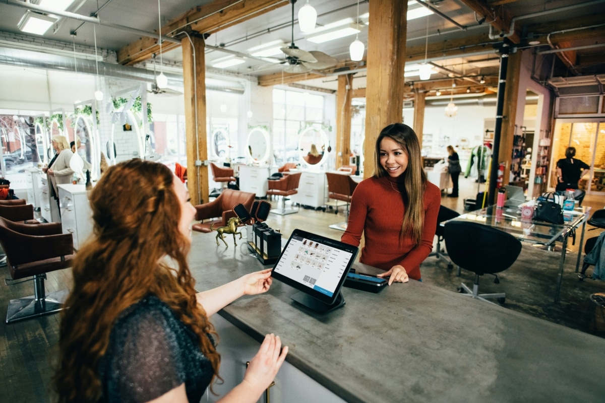 Two female coworkers at a salon reception counter.