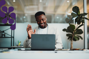 A smiling businessman in a modern-looking glass office having a virtual coaching session.