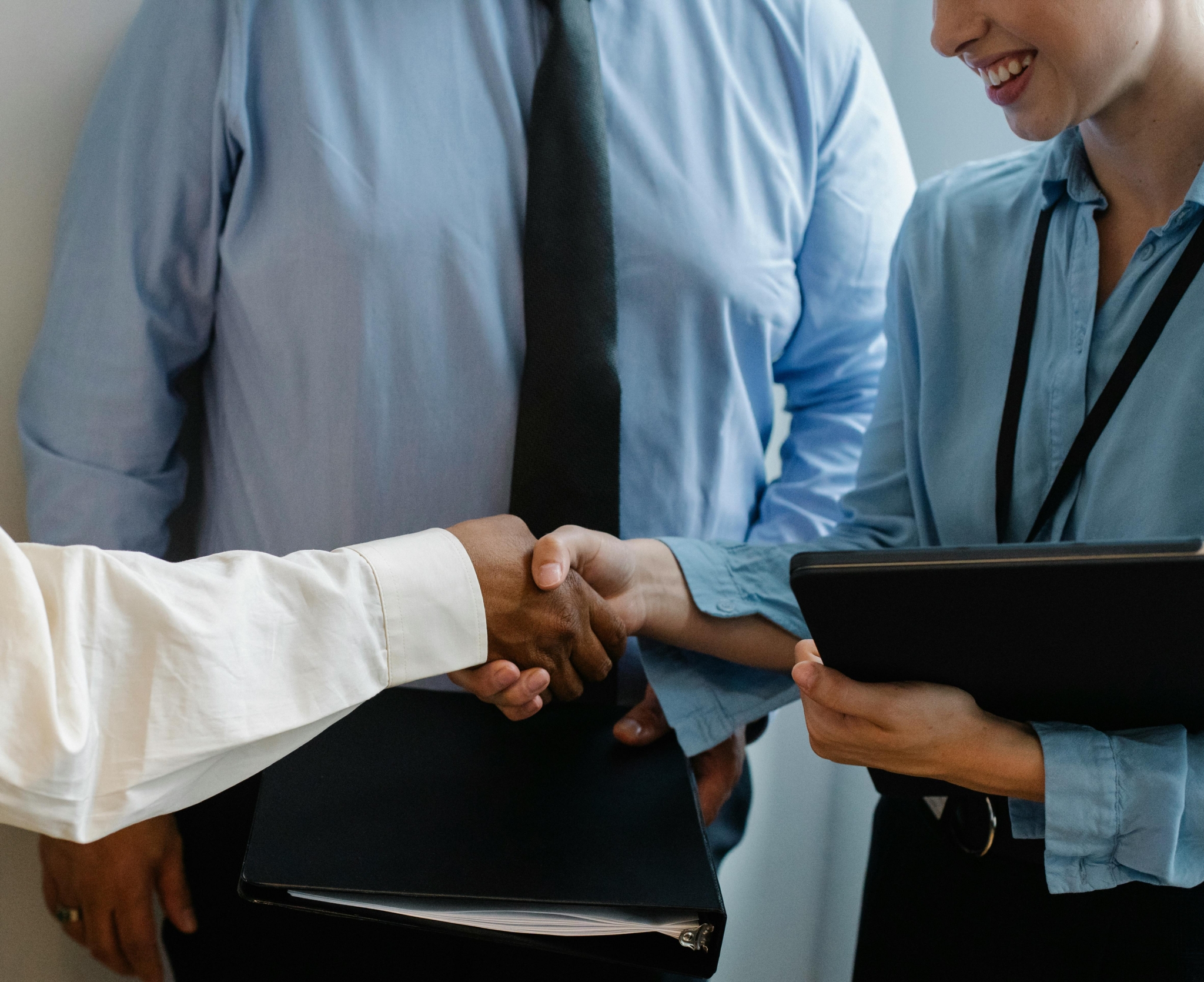 Employees shaking hands in front of another employee.